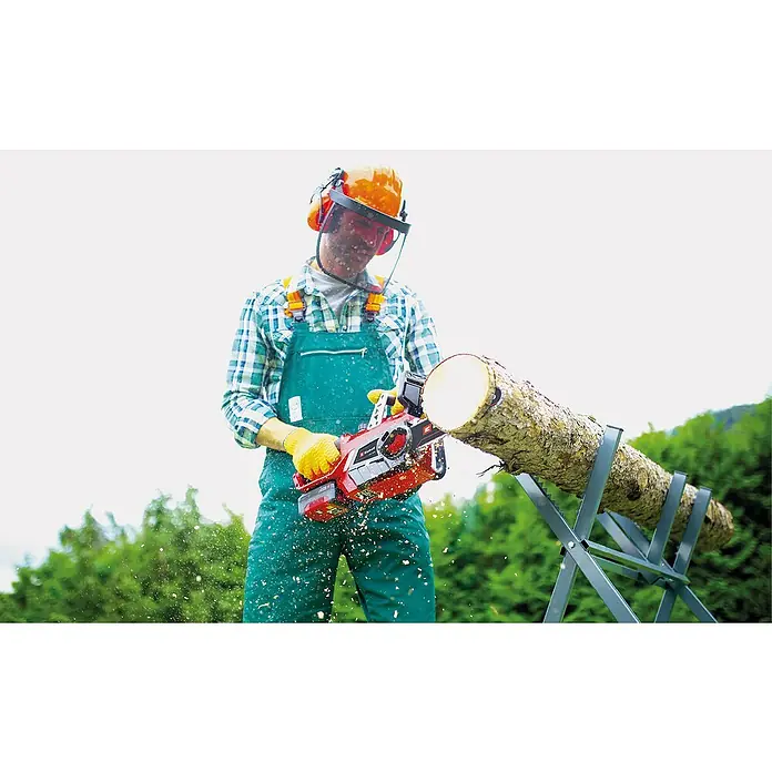 Einhell Power X-Change 18V Akku-Kettensäge GE-LC 18/25 Li-Solo - 18 V, Ohne Akku, Schwertlänge: 25 cm - Ein Mann mit Schutzkleidung sägt mit einer roten Akku-Kettensäge einen Baumstamm auf einem Sägebock.