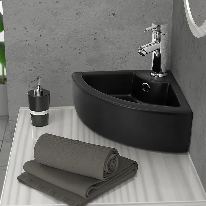 LuxeBath Aufsatzwaschbecken Waschtisch aus Keramik für Badezimmer / Gäste-WC - 33 x 46 cm, Ohne Spezialglasur, Schwarz - Nahaufnahme eines stilvollen schwarzen Eckwaschbeckens mit Handtüchern und Seifenspender, das modernes Baddesign zeigt.