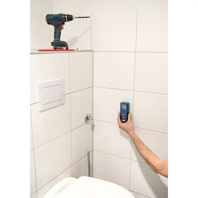 Alpha Tools Metall- & Holzsuchgerät Multi-Detektor - Betriebstemperatur: 0 °C - 40 °C - Handwerker verwendet einen Detektor, um die Wand auf Rohre oder Kabel zu überprüfen, bevor er mit einer Bohrmaschine ein Loch bohrt.