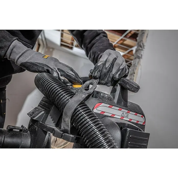 DeWalt Elektro-Nass- & Trockensauger DXV30SAPTA - 1.050 W, Behältervolumen: 30 l, Filterreinigung: Vollautomatisch - Ein Arbeiter, der mit Handschuhen ausgestattet ist, montiert einen Staubsaugerschlauch an einer DeWalt-Maschine. Perfekt für saubere Arbeitsbereiche.