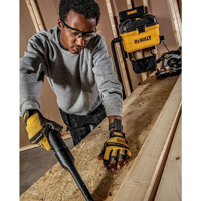 DeWalt Elektro-Nass- & Trockensauger DXV23G - 230 W, Behältervolumen: 23 l - Ein Mann mit DeWalt-Handschuhen und Schutzbrille verwendet einen DeWalt-Staubsauger für seine Holzarbeiten.