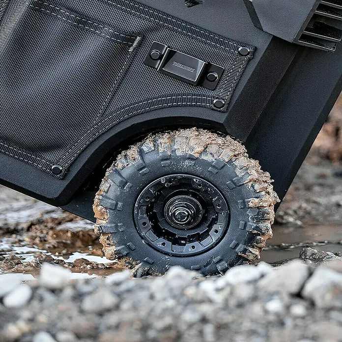 ToughBuilt Caja profesional con ruedas Massive Mouth® - 18'', L x An x Al: 370 x 525 x 500 mm - Primer plano de un producto ToughBuilt con neumático robusto en un entorno off-road, ideal para entornos de trabajo duros.