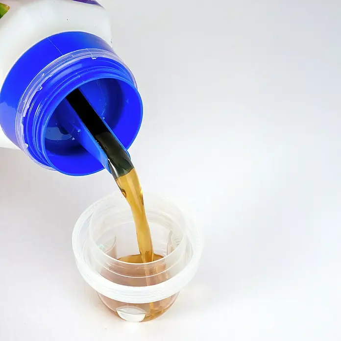 Compo Orchideendünger - 250 ml - Abgefülltes Waschmittel: Flüssiges Waschmittel wird in einen Messbecher gegossen, um die richtige Dosierung für die Wäsche zu gewährleisten.