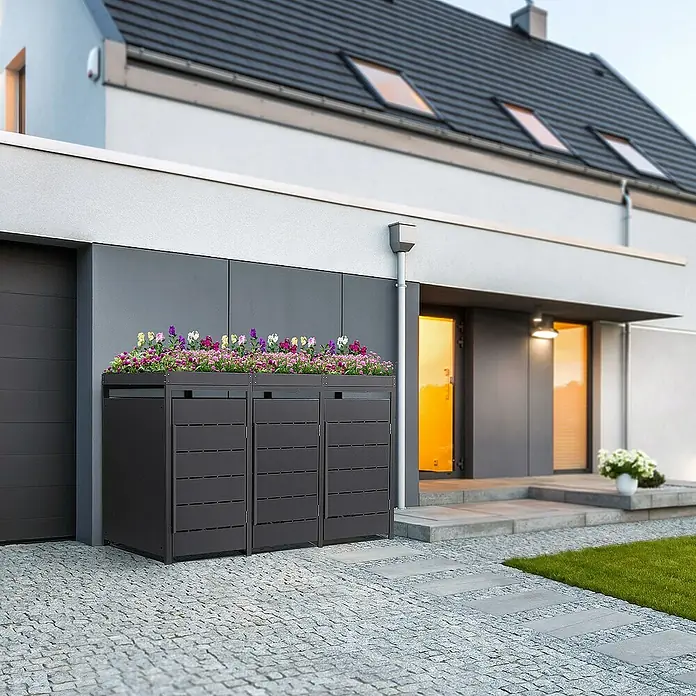 ML-Design Mülltonnenbox Mülltonnencontainer mit Pflanzdach für 3 Tonnen 120 oder 240 Liter - 80 x 80 cm, Stahl, Anthrazit, Geeignet für Anzahl Mülltonnen: 3 Stk. - Drei graue Mülltonnenboxen mit Blumenschmuck vor einem modernen Haus. Ideal zur stilvollen Mülltrennung und Gartendekoration.