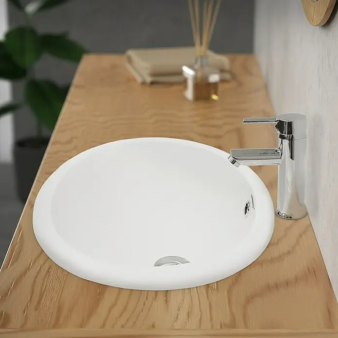 LuxeBath Einbauwaschbecken Handwaschbecken Weiß inkl. Ablaufgarnitur mit Überlauf - 40,5 x 49 cm, Mit Überlauf, Weiß - Aufsicht auf ein rundes, weißes Waschbecken mit modernem Chromhahn auf einer hellen Holzoberfläche im Badezimmer.
