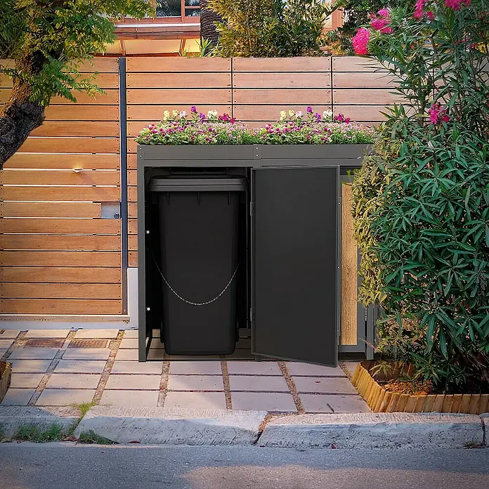 ML-Design Mülltonnenbox Mülltonnencontainer mit Pflanzdach für 3 Tonnen 120 oder 240 Liter - 80 x 80 cm, Stahl, Eiche hell, Geeignet für Anzahl Mülltonnen: 3 Stk. - Schwarze Mülltonnenbox mit Pflanzkasten auf einem gepflasterten Weg, teilweise geöffnet.