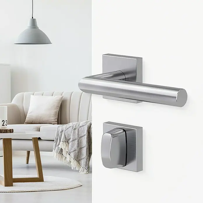 Diamond Doors Modern Drückergarnitur WC Quattro L-Form - Edelstahl, L-Form, Stärke Tür: 38 mm - 45 mm, Schlitzkopf/Olive - Nahaufnahme einer modernen Türschnalle aus gebürstetem Stahl in einem hellen Wohnraum. Elegantes Design für ein stilvolles Zuhause.