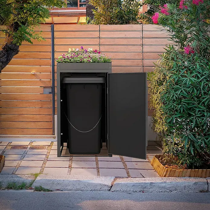 ML-Design Mülltonnenbox Mülltonnencontainer mit Pflanzdach für 1 Tonne 120 oder 240 Liter - Stahl, Eiche dunkel, Geeignet für Anzahl Mülltonnen: 1 Stk. - Diese Aufnahme zeigt einen Mülltonnenständer mit Bepflanzung. Praktische Mülltonnenbox mit Blumenkasten auf einem gepflasterten Weg.