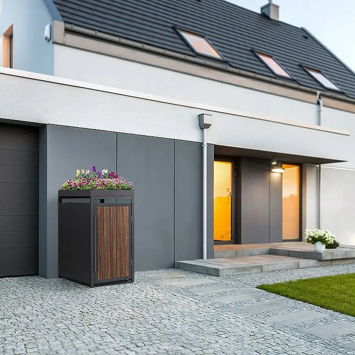 ML-Design Mülltonnenbox Mülltonnencontainer mit Pflanzdach für 1 Tonne 120 oder 240 Liter - Stahl, Eiche dunkel, Geeignet für Anzahl Mülltonnen: 1 Stk. - Moderne Mülltonnenbox mit Pflanzkasten auf einem gepflasterten Hof vor einem modernen Haus.