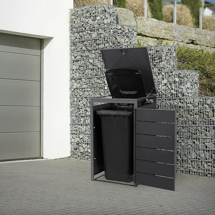 ML-Design Mülltonnenbox Mülltonnencontainer mit Klappdeckel/Tür für 1 Tonne 120 oder 240 Liter - Stahl, Anthrazit, Geeignet für Anzahl Mülltonnen: 1 Stk. - Mülltonnenbox aus Metall mit geöffnetem Deckel und Tür, die eine schwarze Mülltonne zeigt, vor einem Haus mit Steinkorb.