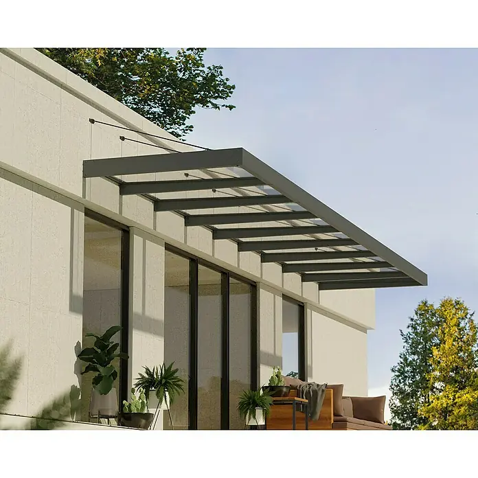 Palram – Canopia Pultvordach Sophia XL - 845 x 140 x 17 cm, Anthrazitgrau, Farbe Dach: Klar - Bild eines modernen Vordachs aus dunklem Metall und Glas, das über einer Terrasse mit Pflanzen und Sitzgelegenheiten angebracht ist.