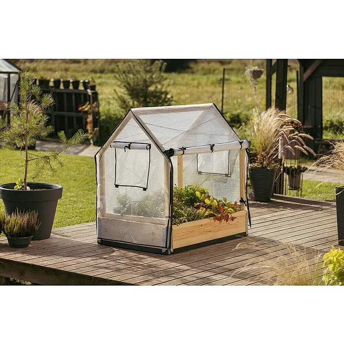 Upyard Hochbeet-Überdachung Schutzrahmen inkl. 3 Abdeckungen - Passend für: Hochbeete 120 × 80 cm - Ein kleines Gewächshaus aus Holz und Kunststofffolie steht auf einer Holzterrasse, gefüllt mit Pflanzen.