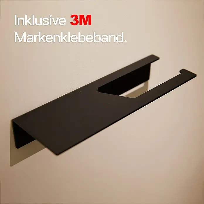 Designfabrik Hamburg Toilettenpapierhalter - Mit Ablage, Schwarz, Matt - Das Foto zeigt einen schwarzen Handtuchhalter aus Metall, der mit 3M-Markenklebeband an einer hellen Wand befestigt ist.