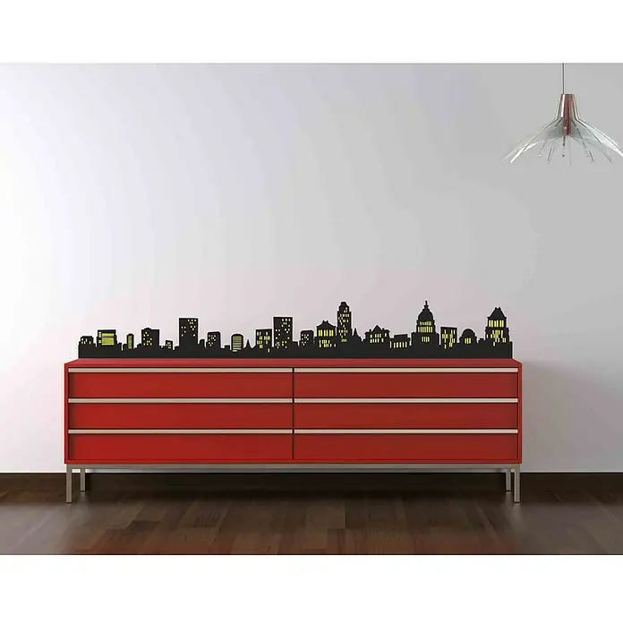 Vinilo de pared - Casas en la noche, Negro, Plástico - Una cómoda roja con seis cajones, decorada con una silueta negra de horizonte urbano, sobre una pared blanca.