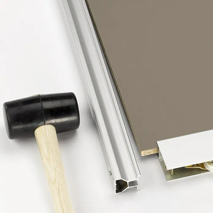Room Plaza Easy Schiebetür-Bau-Set - Taupe/Weiß Miniperl, Farbe Beschlag: Silber - Ein schwarzer Gummihammer liegt neben einer Aluminiumleiste und einer Platte. Ideal für die Montage von Möbeln und Paneelen.