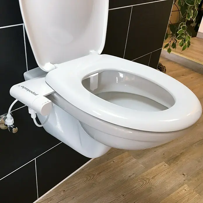 Popodusche WC-Aufsatz - Weiß - Nahaufnahme einer weißen Toilette mit Bidet-Aufsatz, installiert in einem modernen Badezimmer mit schwarzen Fliesen und Holzboden.