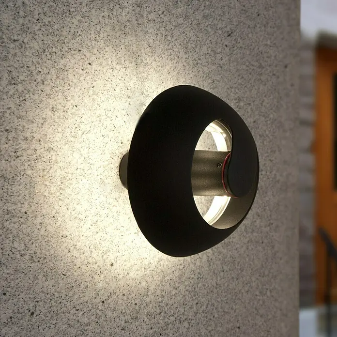 Lutec Aplique exterior LED Spril - 8,4 W, 19,5 x 19,6 x 16,6 cm, Antracita, IP54 - Primer plano de una moderna lámpara de pared negra, que emite una luz cálida y crea un ambiente elegante.