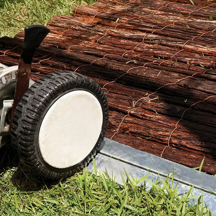 Palram – Canopia Gewächshaus Balance - Außenmaß inkl. Dachüberstand (B x T): 244 x 367 cm, 0,75 mm, Silber - Nahaufnahme eines Gartenwagens mit einem Rad im Gras, vor einem Holzhintergrund.