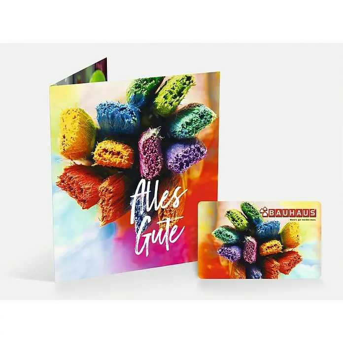 Gutscheinkarte - Per Postversand, Individueller Betrag, Bunte Pinsel - Grußkarte mit bunten Pinseln und Schriftzug "Alles Gute" neben einer Bauhaus Geschenkkarte.