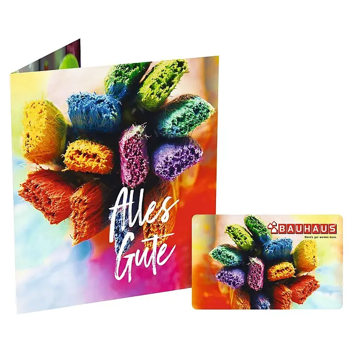 Gutscheinkarte - Per Postversand, 20 Euro, Bunte Pinsel - Grußkarte mit bunten Pinseln und Schriftzug "Alles Gute" neben einer Bauhaus Geschenkkarte.