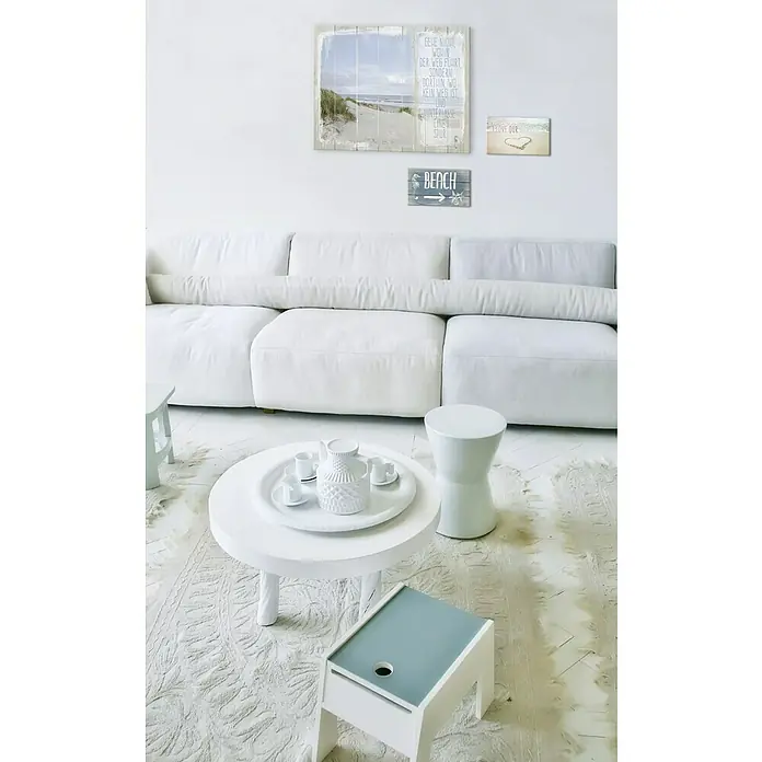 ProArt Type Hype Decopanel - Beach, B x H: 30 x 15 cm - Ein helles Wohnzimmer mit einem großen weißen Sofa, einem runden Tisch mit Teegeschirr und dekorativen Wandbildern, die eine entspannende Atmosphäre schaffen.