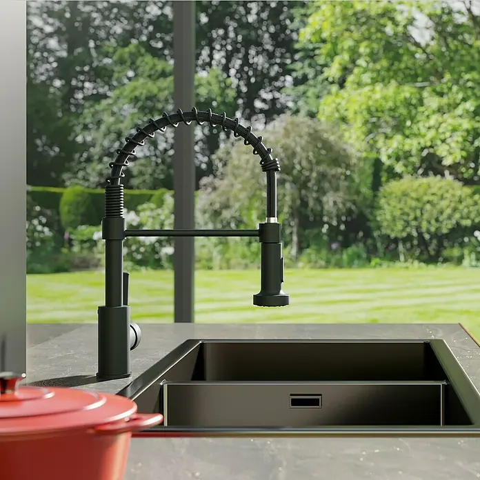 Lenz Spültischarmatur Nova - Schwarz, Matt - Schwarzer Küchenarmatur mit Spiralfeder vor einem Fenster mit Gartenblick. Stilvolles und funktionales Design für moderne Küchen.