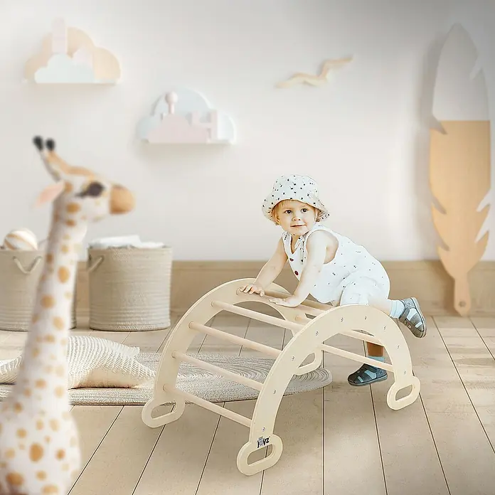 ECD Germany Klettergerüst Kletterbogen trainiert Gleichgewicht & Balance ab 2 Jahren - 89 x 52 x 45,5 cm, Holz, Braun - Ein Kind spielt auf einem hölzernen Kletterbogen in einem hellen Raum, der mit Giraffen- und Wolkendekorationen geschmückt ist.