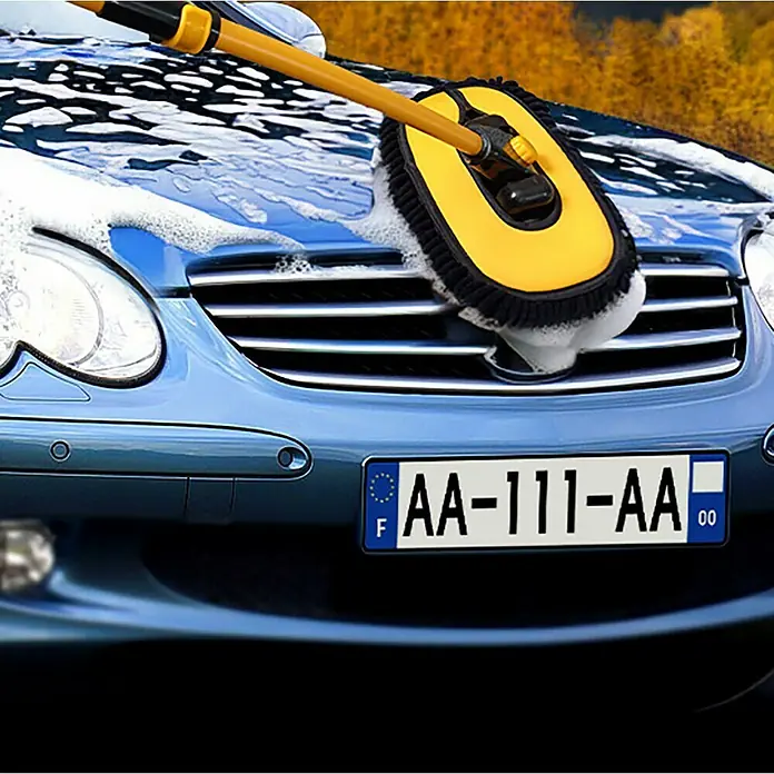 Mopa de microfibra AutoMop - Telescópico - Primer plano de un coche azul que se lava con un accesorio de cepillo amarillo y jabón, centrándose en la herramienta de limpieza.