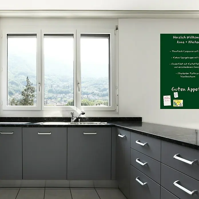 Magnetische Tafelfolie - Grün, 70 x 50 cm, Inkl. 3 Magnete und 3 Stück Kreide - Ein grünes Whiteboard mit einer handschriftlichen Speisekarte in einer modernen Küche, neben einem Fenster mit Blick auf eine Landschaft.