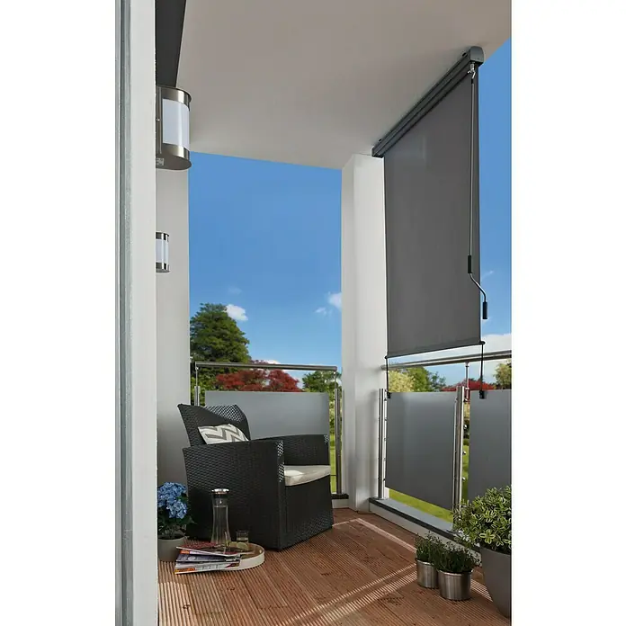 Sunfun Balkonverschattung - Grau, Breite: 1,4 m, Ausfall: 2,5 m - Dieser Balkon verfügt über eine graue, einziehbare Seitenmarkise, die Privatsphäre und Schatten bietet. Ein Sessel und Pflanzen vervollständigen den Raum.