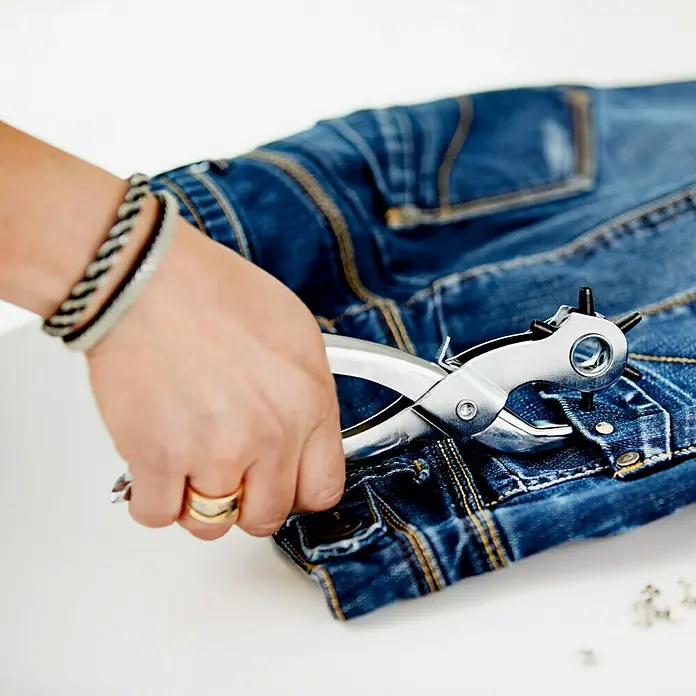Rapid Hohlniete - 8 x 3 x 9 mm, 25 Stk. - Eine Person benutzt eine Revolverzange, um Löcher in ein Paar Jeans zu stanzen, um ein DIY-Mode-Statement zu kreieren.