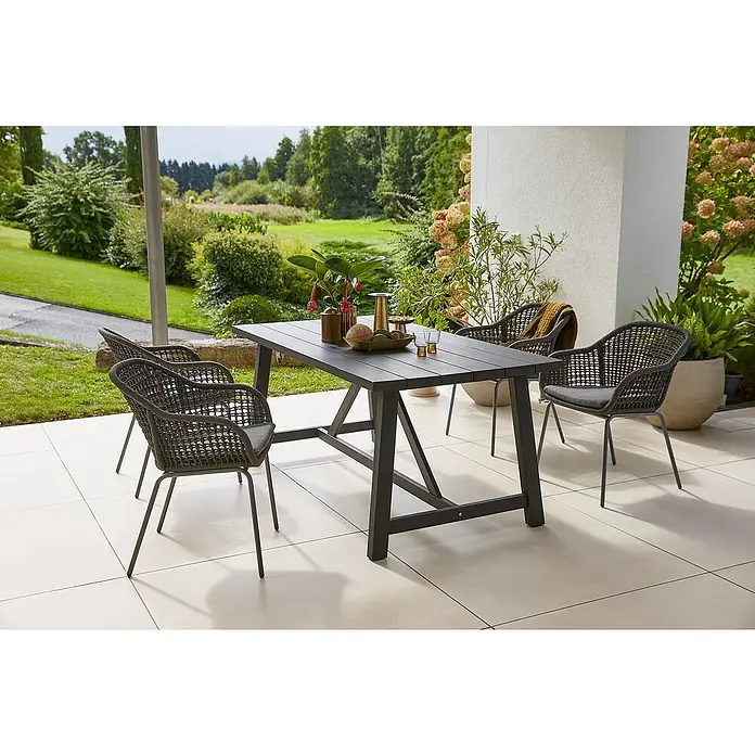 Sunfun Gartenmöbel-Set Melina/Sarah Rope - 5 -tlg., Akazie, Stahl, Olefin, Schwarz/Night-Grey - Gartentischset mit vier Korbstühlen und Tischdekoration. Das Set steht auf einer Terrasse mit Blick in einen Garten.
