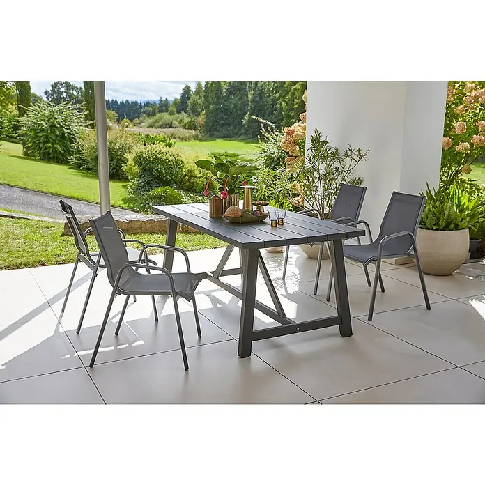 Sunfun Gartenmöbel-Set Melina/Gastro - 5 -tlg., Akazie, Stahl, Textilen, Schwarz/Night-Grey - Ein grauer Gartentisch mit vier Stühlen auf einer Terrasse, umgeben von Grün. Ideal für Mahlzeiten im Freien und Entspannung.