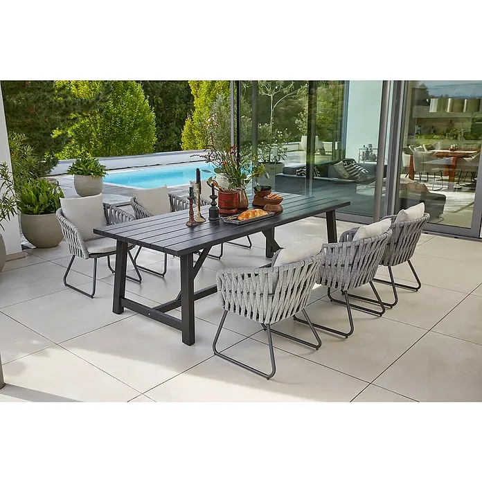 Sunfun Gartenmöbel-Set Melina/Maja - 7 -tlg., Akazie, Seilgeflecht, Schwarz/Grau-Beige - Ein Gartentisch mit Stühlen aus Rattan und hellen Polstern steht auf einer Terrasse. Im Hintergrund sieht man einen Pool.