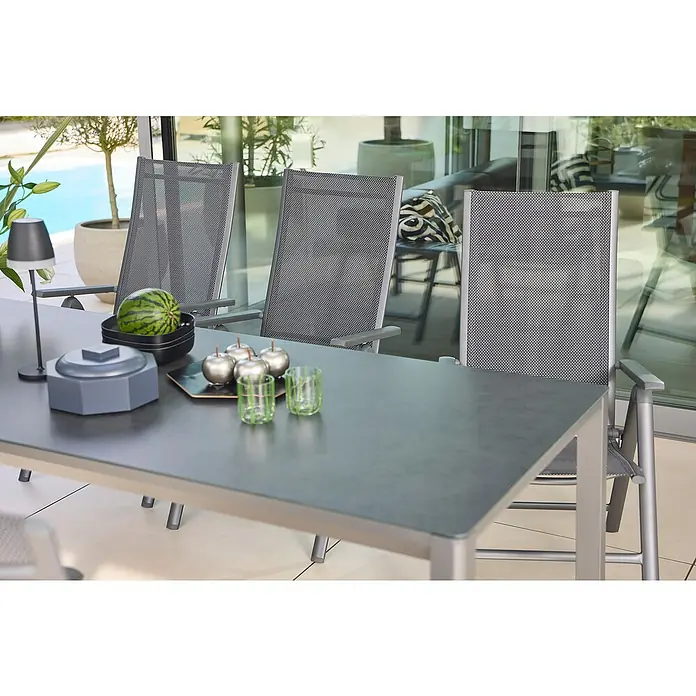 Sunfun Maja Gartentisch - L x B x H: 220 x 90 x 74 cm, Aluminium, Glas, Night-Grey - Eine elegante Gartentischszene mit stilvollen Stühlen, Dekorationen wie Äpfel und Gläsern, die einladend wirkt.