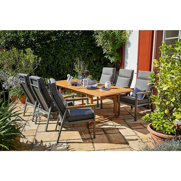 Sunfun Gartenmöbel-Set Diana/Maja - 7 -tlg., Akazie, Aluminium, Polyester, Naturbraun/Night-Grey - Eine stilvolle Gartengarnitur mit einem Holztisch und sechs grauen Stühlen auf einer sonnigen Terrasse, umgeben von üppigem Grün.