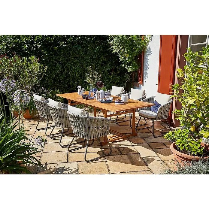Sunfun Gartenmöbel-Set Diana/Maja - 7 -tlg., Akazie, Seilgeflecht, Naturbraun/Grau-Beige - Einladende Gartenszene mit einem Teakholztisch und acht Sesseln mit Seilbespannung, ideal für Mahlzeiten im Freien.