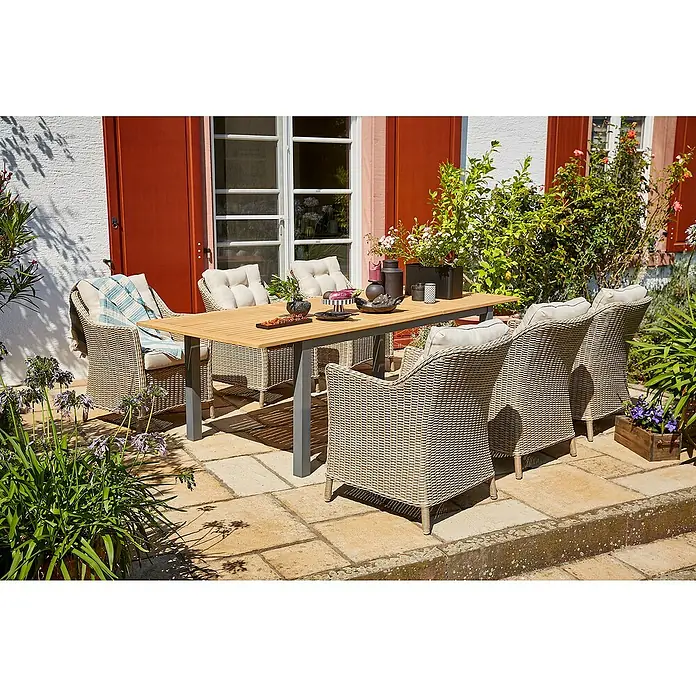 Sunfun Gartenmöbel-Set Carina/Pauline - 7 -tlg., Aluminium, Akazie, Stahl, Polyrattan, Hellbraun/Schwarz - Ein einladender Gartentisch mit Stühlen auf einer Terrasse, umgeben von üppigem Grün, perfekt für Mahlzeiten im Freien.