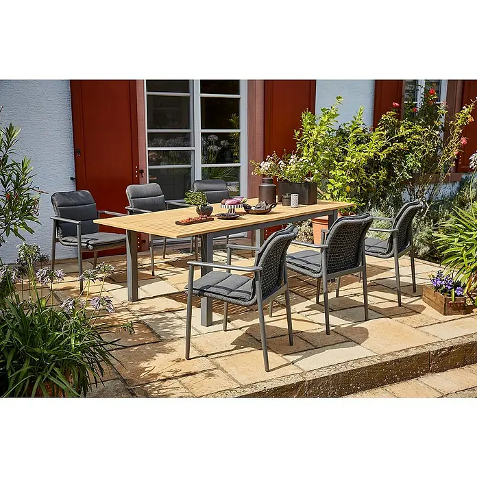 Sunfun Gartenmöbel-Set Carina/Solo Rope - 13 -tlg., Akazie, Aluminium, Stahl, Olefin, Night-Grey/Hellbraun - Einladende Gartenszene mit einem Esstischset, bestehend aus einem Holztisch und sechs grauen Stühlen, umgeben von üppigem Grün.