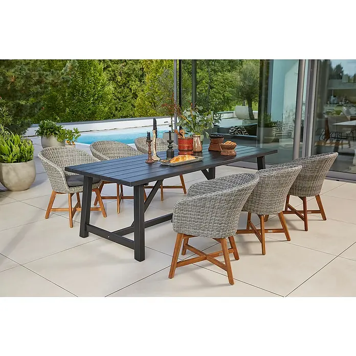 Sunfun Gartenmöbel-Set Melina/Pauline X-Fuß - 7 -tlg., Akazie, Polyrattan, Aluminium, Schwarz/Bambus-Grey - Ein Gartentisch-Set mit schwarzen Tisch und sechs Korbstühlen auf einer Terrasse. Ideal für Mahlzeiten im Freien.