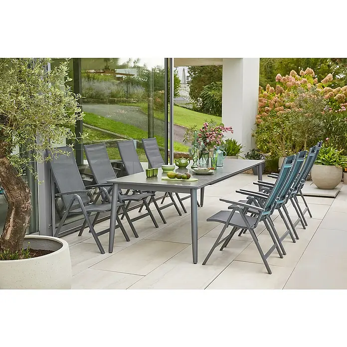 Sunfun Gartenmöbel-Set Solo/Maja - 9 -tlg., Aluminium, Sintered Stone, Textilen, Anthrazit/Night-Grey - Graue Gartentischgarnitur mit Armlehnstühlen im Außenbereich, umgeben von Pflanzen und mit Dekorationen auf dem Tisch.