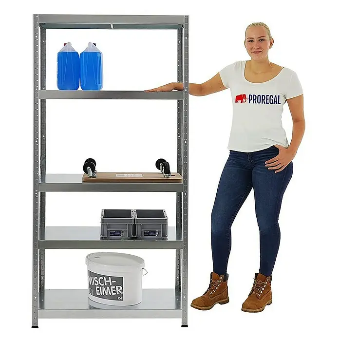 Proregal Metallregal Steel Eagle - H x B x T: 180 x 90 x 40 cm, Traglast pro Boden: 130 kg, Anzahl Böden: 5 Stk., Stecken, Verzinkt - Ein silbernes Schwerlastregal mit fünf Regalböden und diversen Gegenständen darauf, daneben steht eine Frau.
