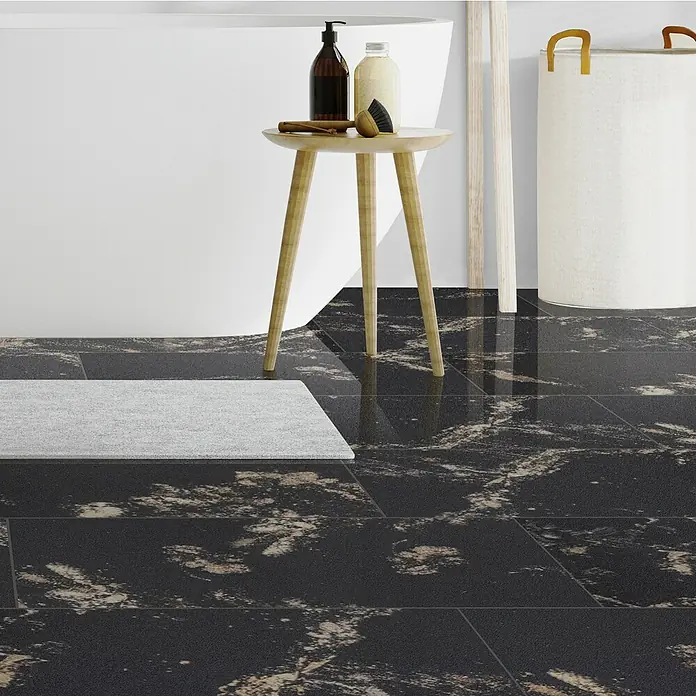 Opiart Feinsteinzeugfliese Oro - 29,7 x 59,7 cm, Schwarz/Gold, Glänzend - Nahaufnahme der glänzenden Bodenfliesen in einem Badezimmer mit Badewanne, Beistelltisch und Wäschekorb.