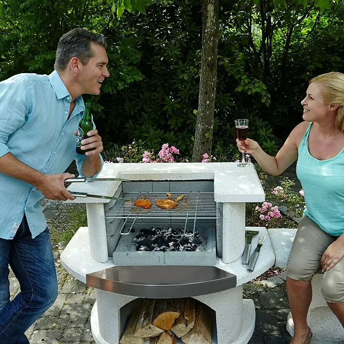 Buschbeck Grillbar Venedig - Edelstahlsimsblech, Hauptgrillfläche: 54 x 34 cm - Auf diesem Bild ist ein Grill zu sehen, während ein Paar ein Getränk zu sich nimmt.