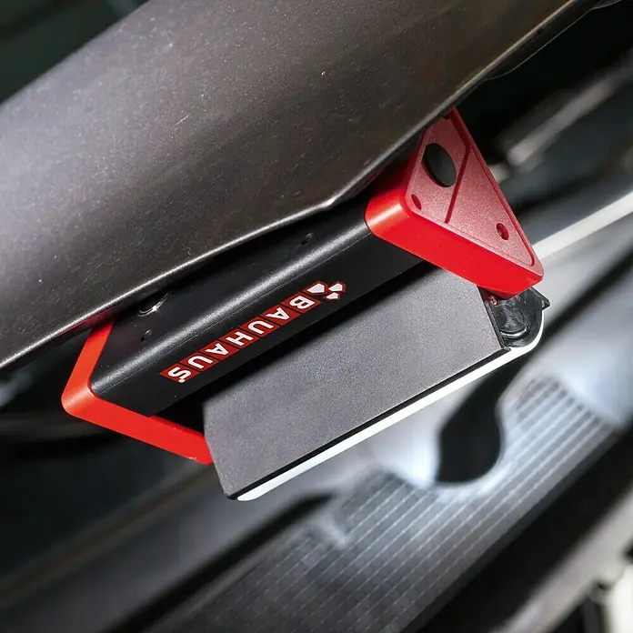 BAUHAUS Mobiles LED-Licht Dreieck - Batteriebetrieben, Schwarz/Rot, 150 lm - Nahaufnahme einer Bauhaus-Arbeitsleuchte mit rotem Akzent und schwarzem Gehäuse, montiert unter einer Oberfläche.