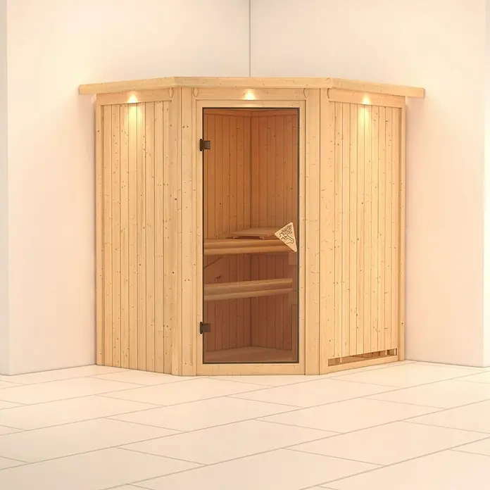 Karibu Elementsauna Tonja - Ohne Ofen, Mit Dachkranz und Beleuchtung, L x B x H: 184 x 165 x 192 cm - Innenaufnahme einer Ecksauna aus hellem Holz mit Glastür und Bänken, die eine entspannende Wellness-Oase verspricht.