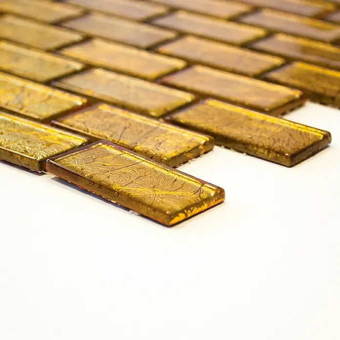 Mosaikfliese Brick Crystal Uni CM 4GO30 - 30 x 30 cm, Gold, Glänzend - Nahaufnahme von rechteckigen, schimmernden Goldfliesen, die ein elegantes und luxuriöses Muster auf einer hellen Oberfläche bilden.