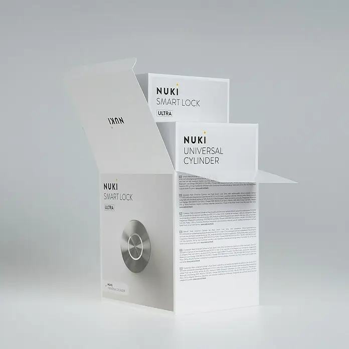 Nuki Elektronisches Türschloss Smart Lock Ultra - Bedienung: Über App, Geeignet für: Türen - Offene Verpackung eines Nuki Smart Lock Ultra und Universal Cylinder Sets, die Details und das Produkt selbst zeigt.