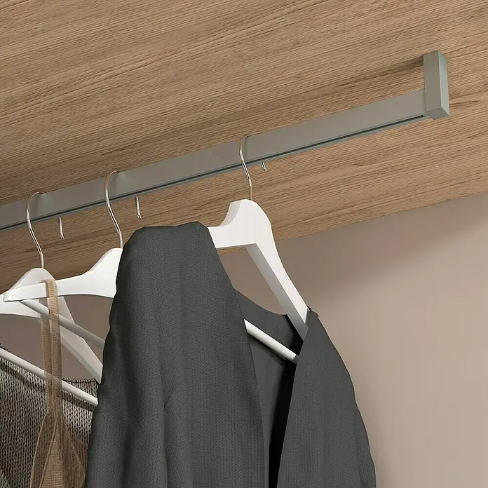 Emuca Kleiderstangen-Set Luxe - Länge: 75 cm, Steingrau - Kleiderbügel an einer Kleiderstange im Kleiderschrank. Die Kleiderbügel sind weiß und die Kleidung dunkel. Die Stange ist silbern.
