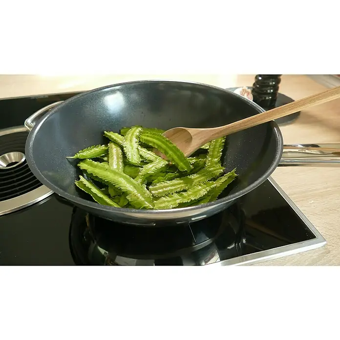 Blu Bio Spargelerbse - Lotus tetragono, Topfgröße: 12 cm - Gebratene Flügelbohnen in einem Wok mit einem Holzlöffel auf einem modernen Kochfeld.